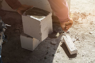 Cropped hands of person arranging bricks at construction site