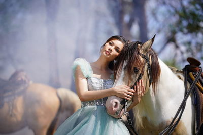 Portrait of a beautiful woman with a horse in the forest background.