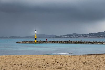Lighthouse by sea against sky