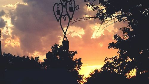 Low angle view of silhouette trees against orange sky