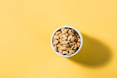 Salted peanuts in a white bowl on a delt background in hard light. healthy modern vegetarian food