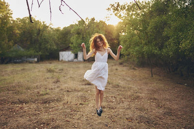 Full length rear view of woman with arms raised