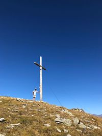 Low angle view of summit cross  on land against clear blue sky