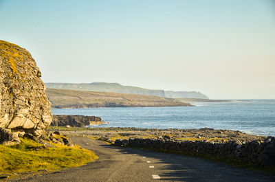 Road by sea against clear sky