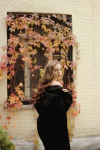 Side view portrait of young woman standing by window