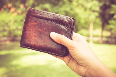 Close-up of person holding wallet outdoors