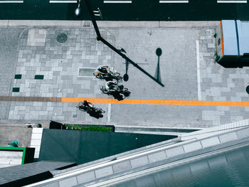 High angle view of men riding bicycle on sidewalk during sunny day