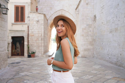 Portrait of smiling attractive woman walking alone in the medieval town of barletta, apulia, italy
