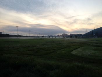 Scenic view of grassy field against cloudy sky
