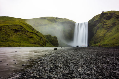 Hikers beneath iceland's famous skogafoss waterfall.