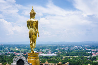 Back of the statue of golden lord buddha is standing on a clear day in summer holiday. 