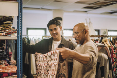 Male fashion designers examining fabric while standing at workshop