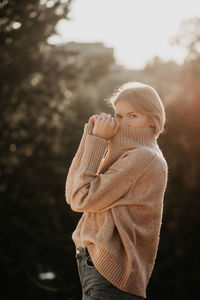 Side view of woman standing against tree