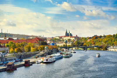 Boats in river by buildings in city against sky