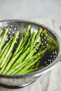 Asparagus in colander on table