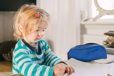 Cute girl looking at empty paper while leaning on table at home