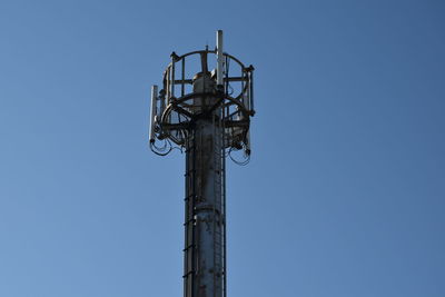 Low angle view of communications tower against clear blue sky