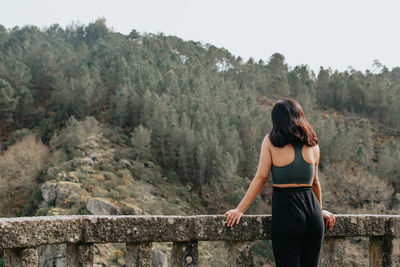 Rear view of woman standing against trees