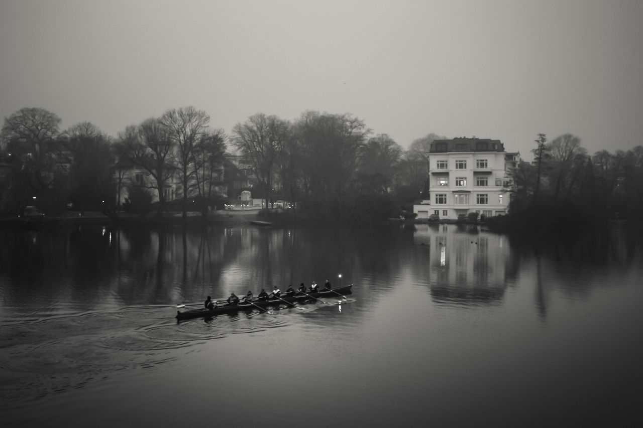 BOATS IN RIVER AGAINST BUILT STRUCTURES