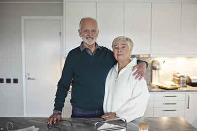 Portrait of senior couple standing by kitchen island at home