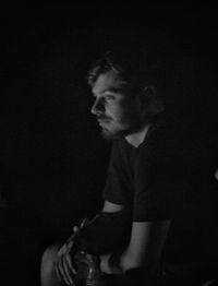 Side view portrait of a young man on black background