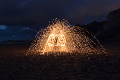 Light trails on beach against sky at night