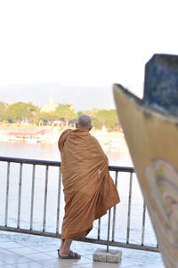 Rear view of man looking at railing against sky
