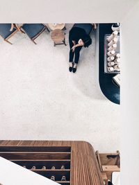 High angle view of woman sitting by chairs in cafe
