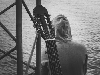 Close-up of guitar with man sitting at shore