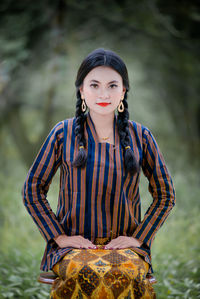 Portrait of young woman standing against sky