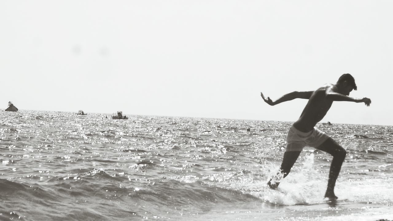 sea, full length, water, leisure activity, lifestyles, horizon over water, beach, childhood, shore, boys, vacations, enjoyment, side view, sky, fun, wave, standing