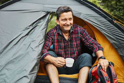 Man relaxing in tent at camping during summer vacation. spending vacations close to nature