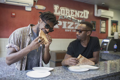 Two young men eating pizza in a restaurant.