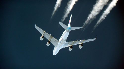 Low angle view of airplane flying against clear blue sky