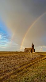 Scenic view of agricultural field against rainbow in sky