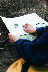 Unrecognizable hiker navigating with map and compass in countryside