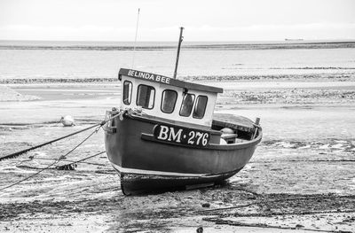 Boat moored at beach against sky