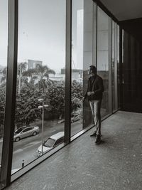 Rear view of man standing by window