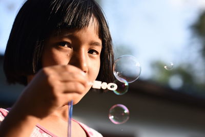 Portrait of girl blowing bubbles outdoors