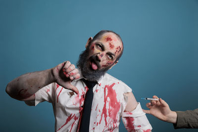 Low angle view of young man with arms raised against black background