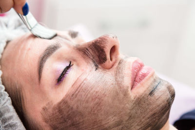 Applying a cream mask for carbon peeling face of an adult woman.