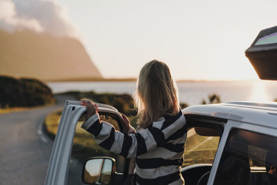 Rear view of woman using mobile phone against sky