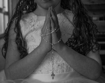 Midsection of girl holding rosary while praying