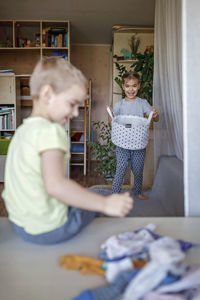 Rear view of brother throwing clothes in bucket