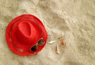 Red straw hat and sunglasses on the sandy beach with tiny seashells