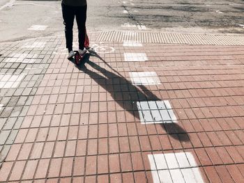 Low section of person riding push scooter on footpath