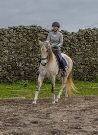 White lusitano horse with female rider, outdoors, horse riding, sport.