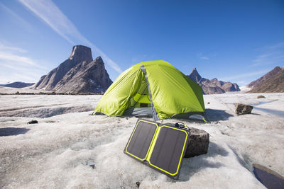 Solar panel charger with tent in background at remote campsite