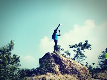 Low angle view of man on rock against sky