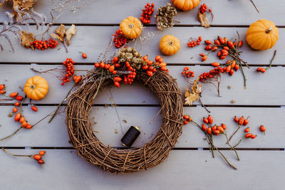 Making floral autumn door wreath from natural materials colorful rosehip berries, rowan, dry flowers